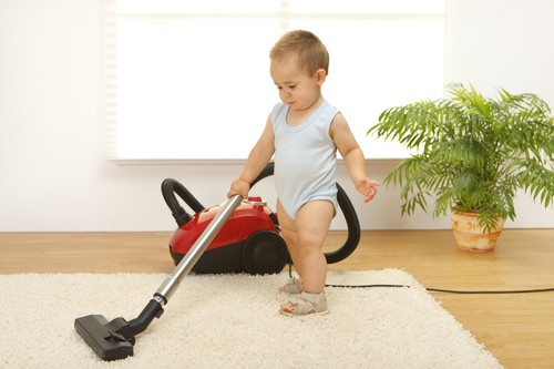 Baby boy cleaning the carpet with vacuum cleaner